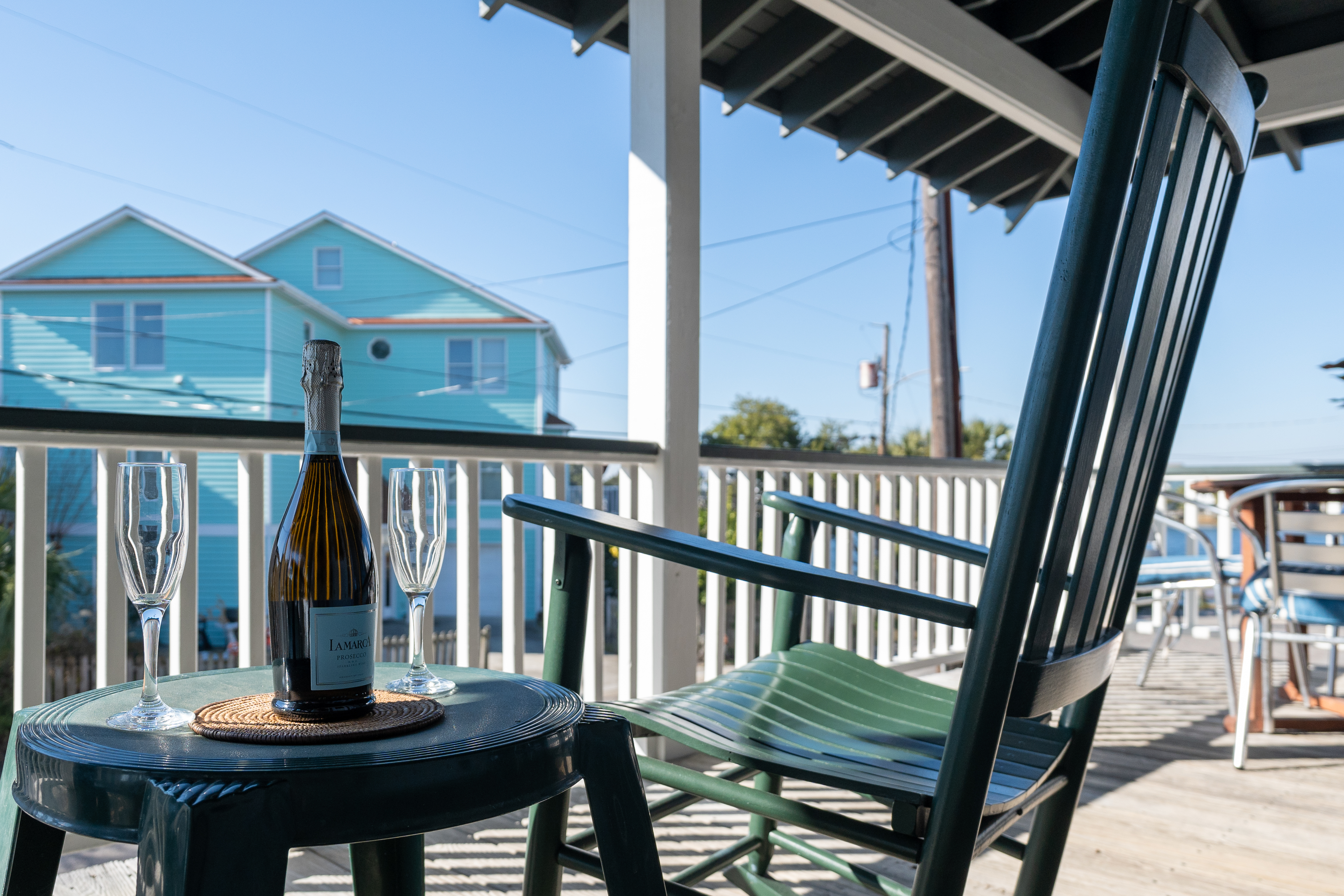 A bottle of prosecco and two glasses on a small porch table