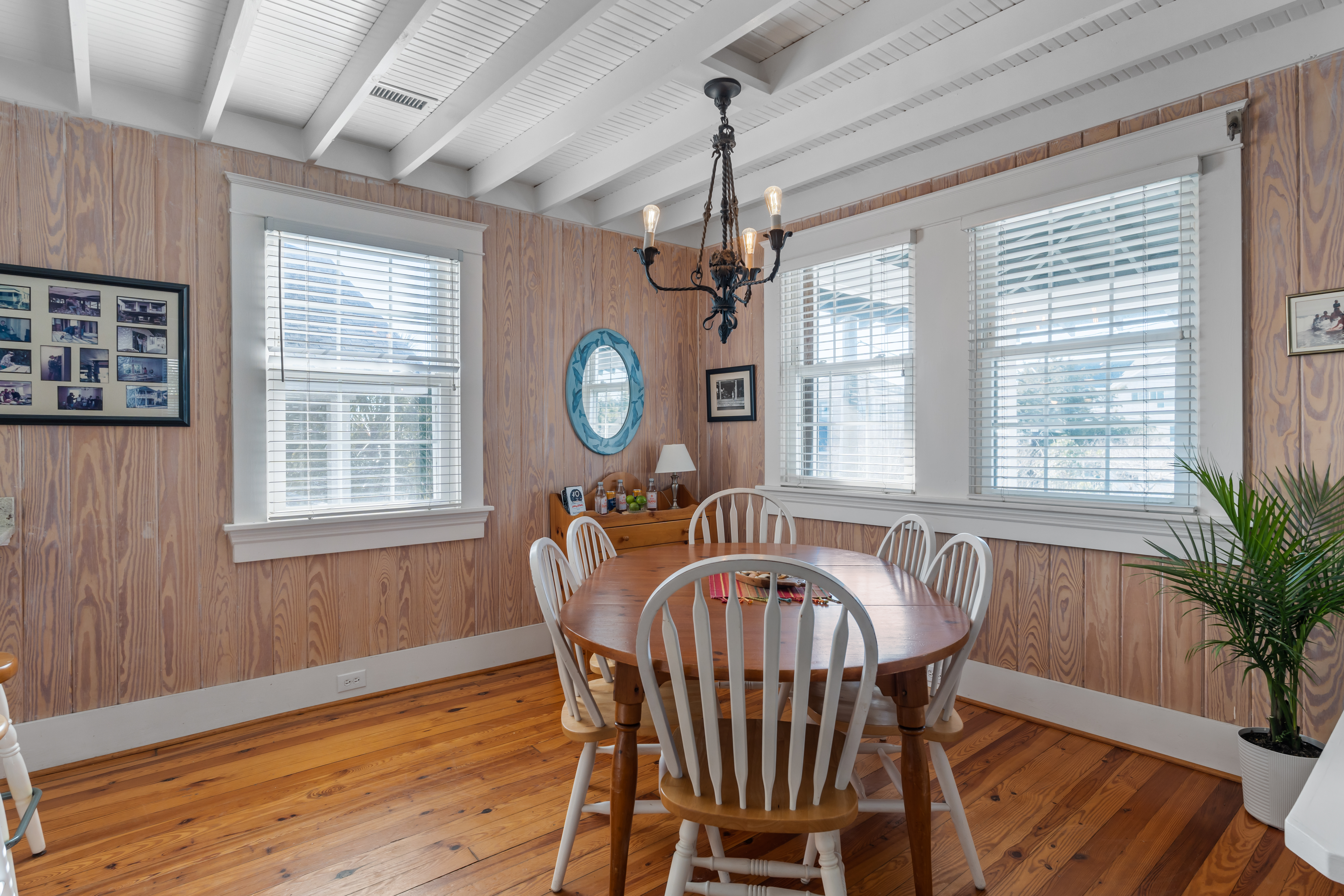 The wood-paneled dining room with a round table and iron chandelier