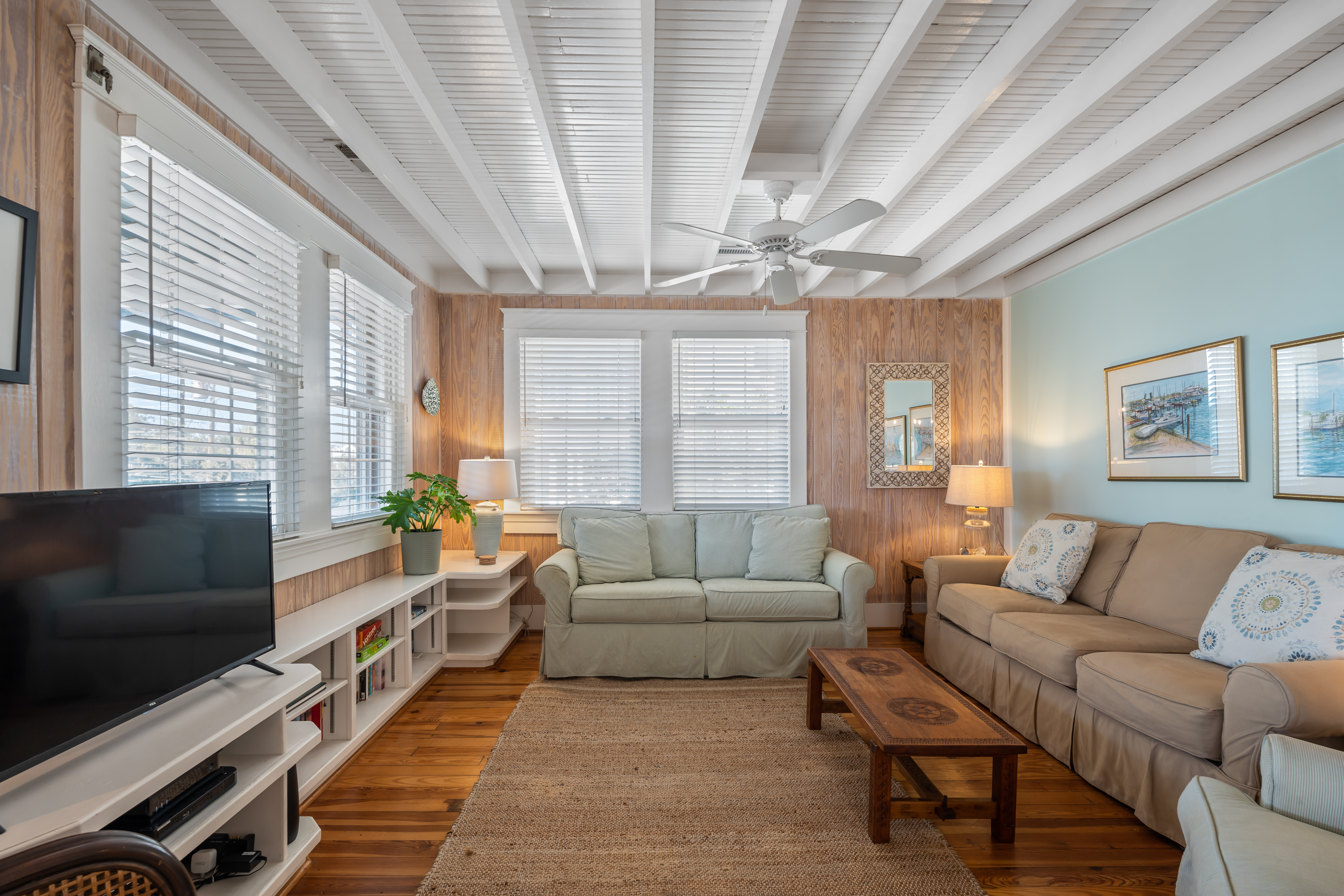 A sitting room with original wood paneling, beadboard ceiling and exposed beams
